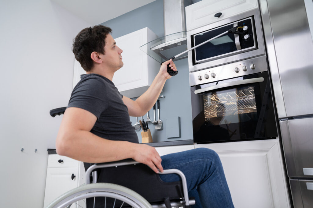 man-uses-adaptive-accessibility-tool-in-Fully-wheelchair-accessible-kitchen-medistays-ndis-mta-medium-term-accommodation