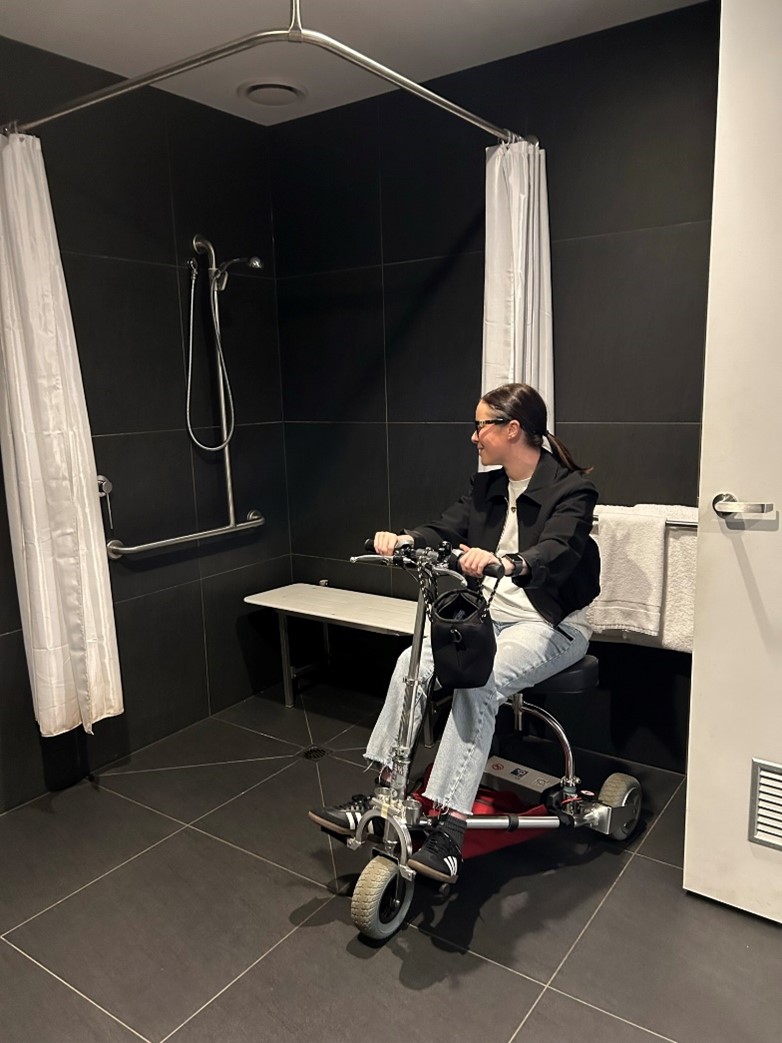 a lady on a mobility scooter in the hotel accessible shower space 