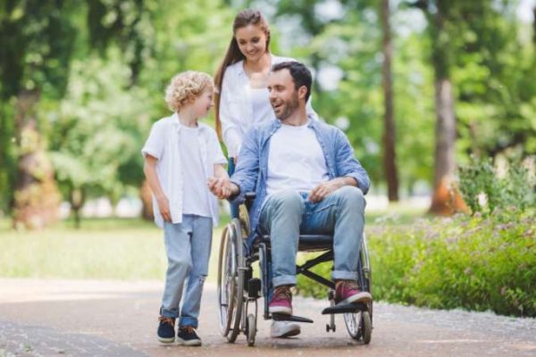 Young man in a wheelchair with his family in the park supported by MediStays hospital accommodation.