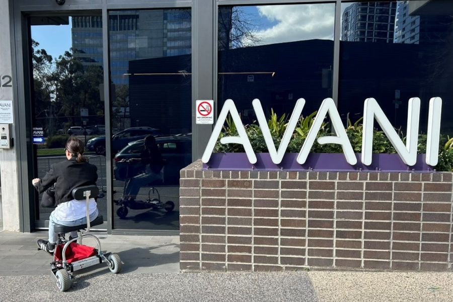 lady on mobility scooter entering the front of a hotel called AVANI