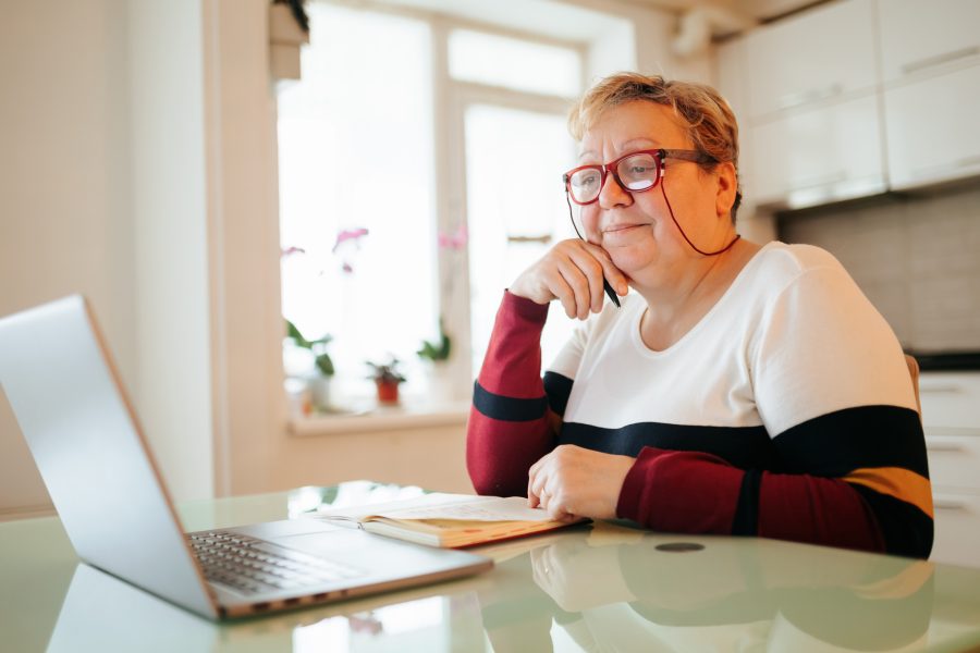 Aged and Wiser An elderly woman, with glasses on, uses her laptop to further her education through e-learning. She sits comfortably at home, taking advantage of technology to enhance her knowledge