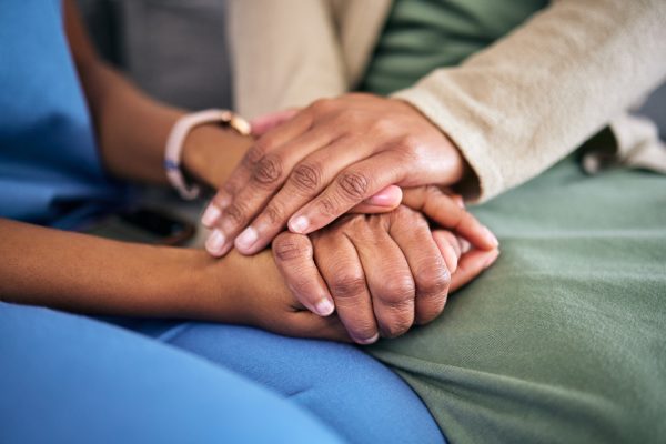 Hands, empathy and helping with life crisis, caregiver with patient for support and grief counseling. People sitting together, healthcare and wellness with advice, kindness and respect with trust